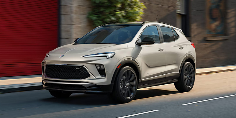 A Buick SUV driving along a bustling city street, showcasing its sleek design and urban environment.