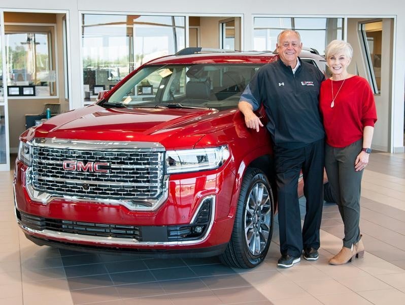Dwight and Susie Everett standing in front of a red GMC suv