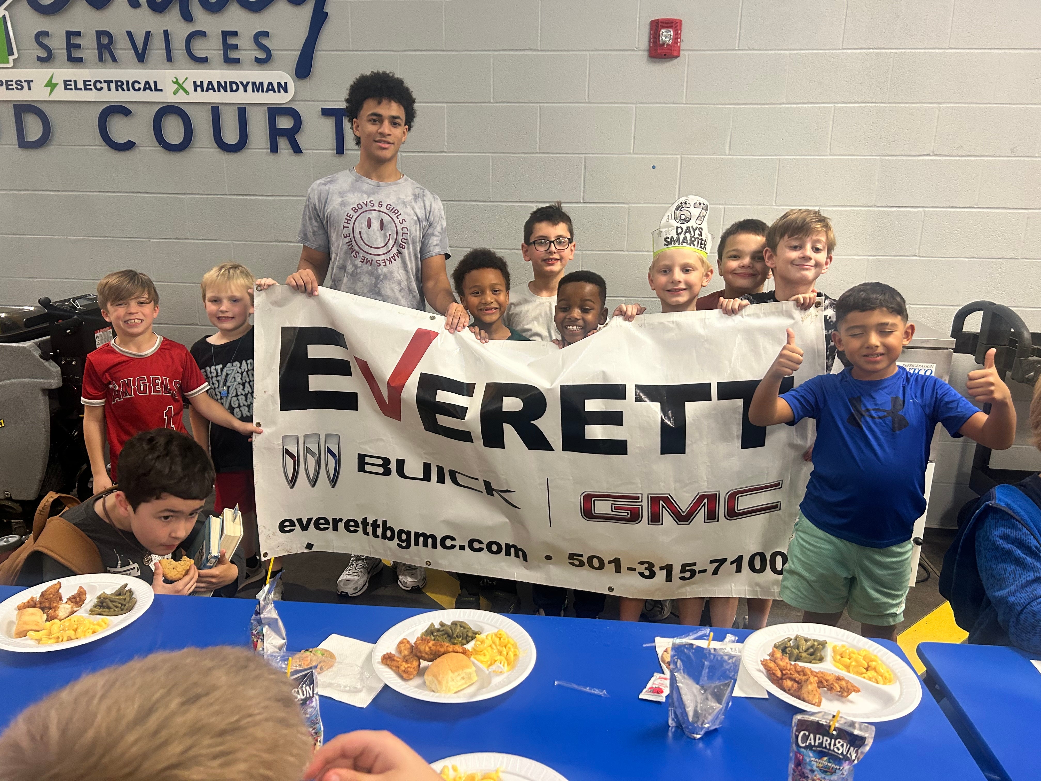 Kids smiling and holding a banner together at a group event.