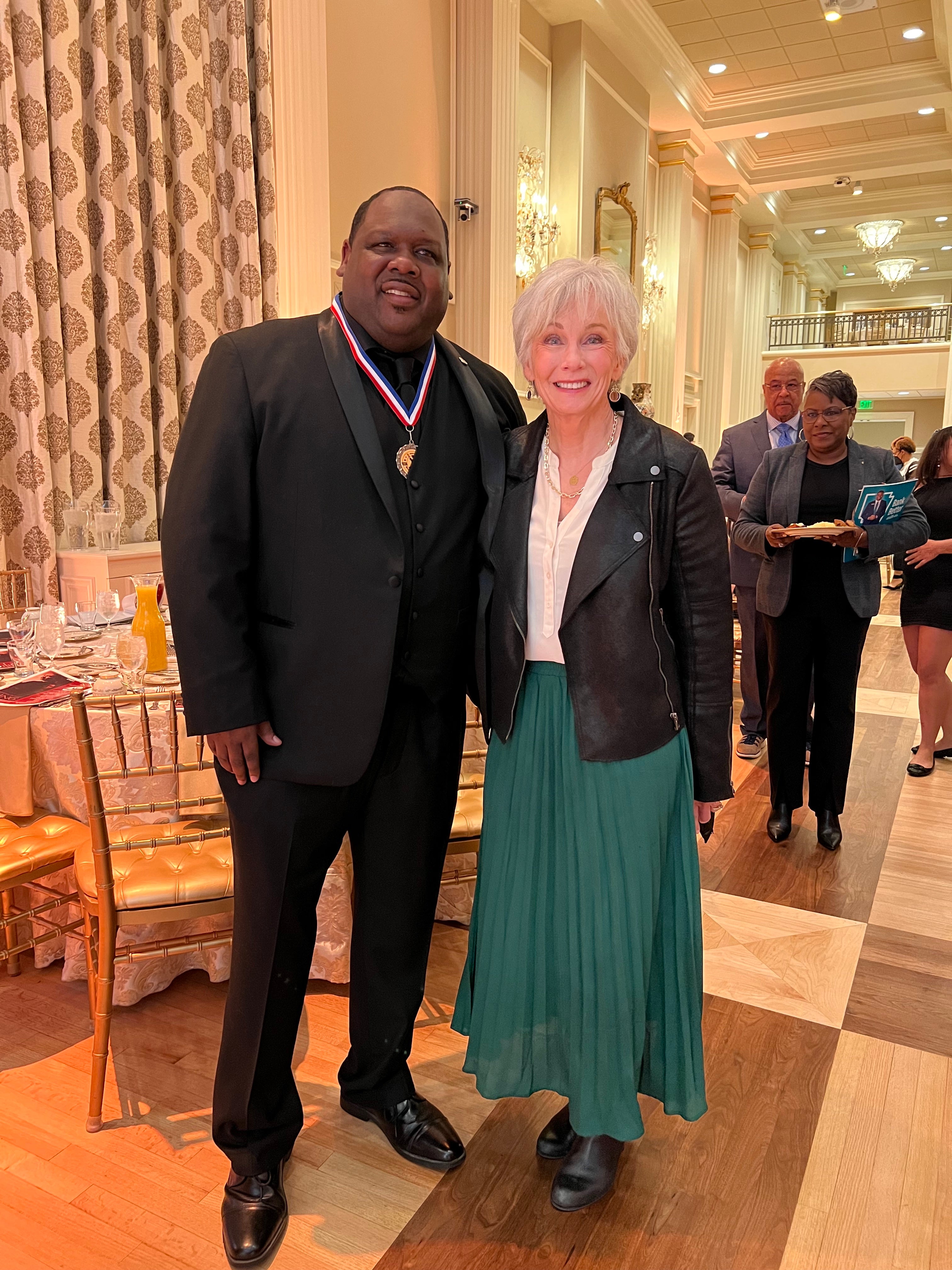 Two formally dressed people smiling together at an elegant banquet event.